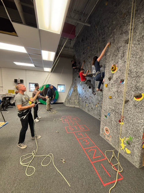 a group of people climbing an indoor rock climbing wall